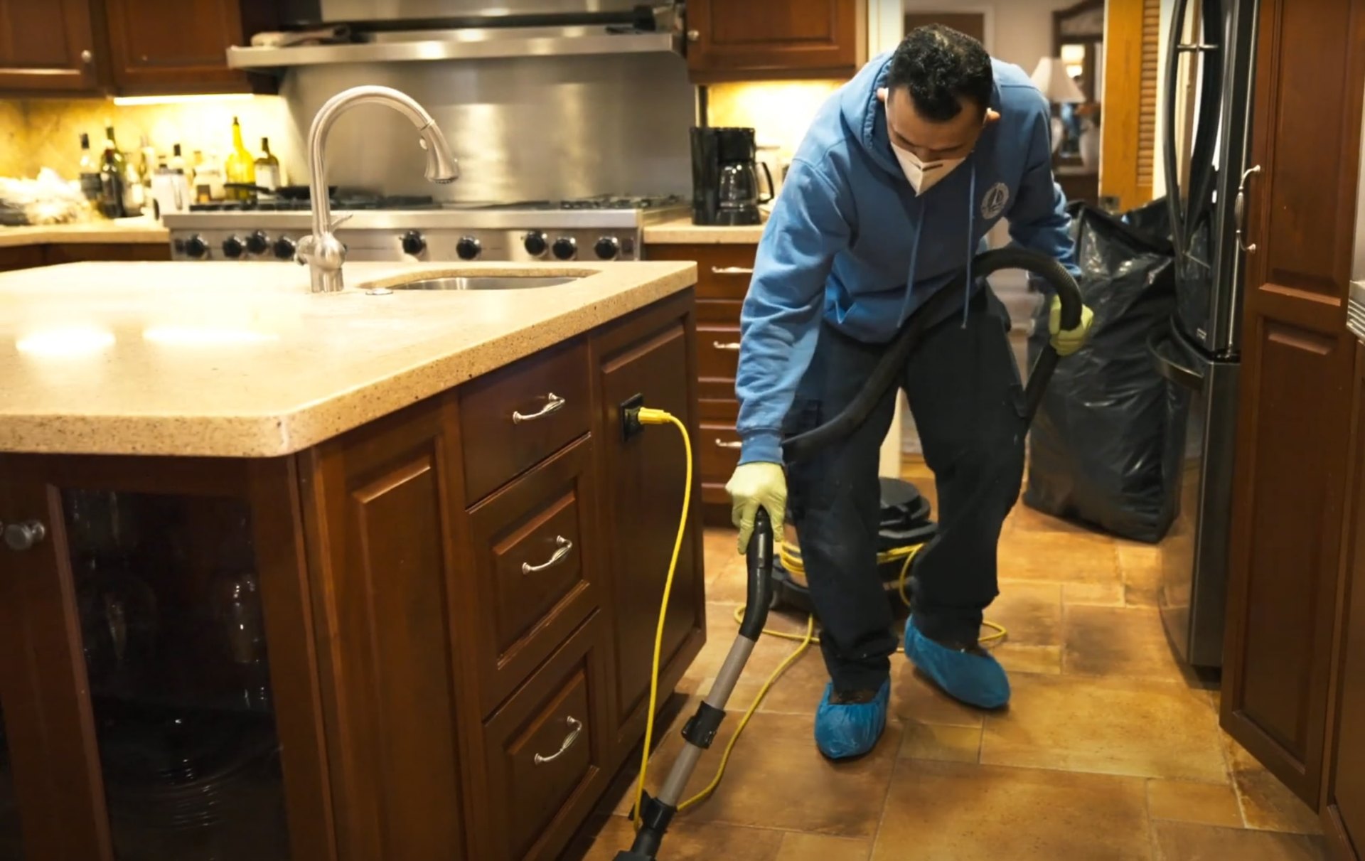 Water damage restoration specialist cleaning flooded kitchen with professional equipment